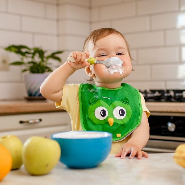 Happy child girl in the kitchen eats a delicious cottage cheese and porridge. Happy child girl in the kitchen eats a delicious cottage cheese and porridge.